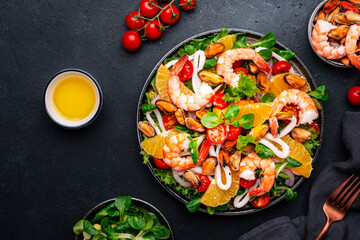 seafood salad with shrimp, mussels, squid, oranges, tomatoes, green lettuce and olemon dressing, top view