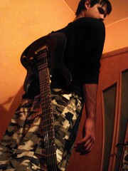 The guy has a black electric guitar hanging on his back.	
