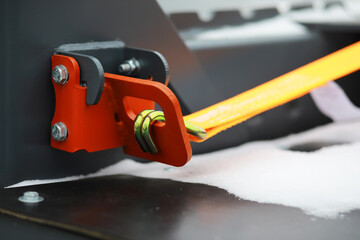 Naklejka premium Close-Up of a Secured Heavy-Duty Orange Strap on Metal Machinery in Snowy Environment