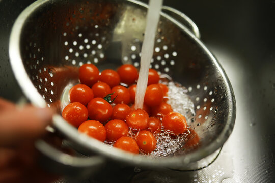 Washing Fresh Cherry Tomatoes in a Colander Under Running Water for a Healthy Salad