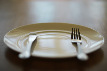 Close-up of Empty Plate with Fork and Knife on Wooden Table - Minimalist Dining Concept