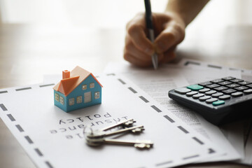 Home Insurance Signing, Key Chain, Miniature House, Contract, Calculator, and Hand Writing