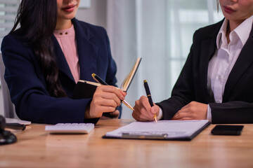 Obraz premium Female executives and female lawyers shake hands at a table in a courtroom to conclude a contract, providing legal advice, teamwork, and professional cooperation.