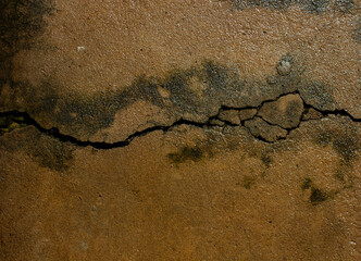 Abstract texture of a crack on a wet, brown clay or concrete surface. Grunge background with natural details