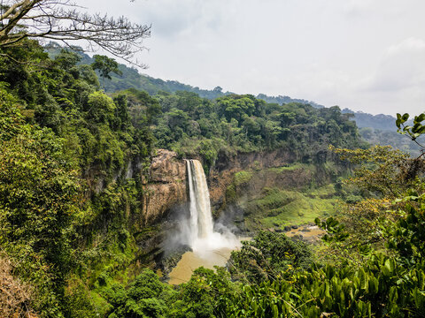 Aerial view of the powerful waterfall cascading down a rocky cliff, surrounded by lush green vegetation, Nkongsamba, Littoral Region, Cameroon.