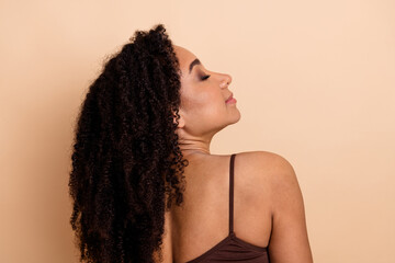 Charming young woman enjoying a moment of serenity against a beige background highlighting her natural beauty