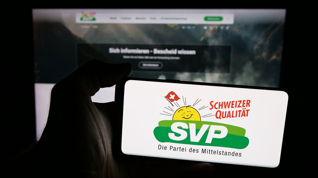 Stuttgart, Germany - 07‑28‑2025: Person holding mobile phone with logo of Swiss party Schweizerische Volkspartei (SVP) on screen in front of web page. Focus on phone display.