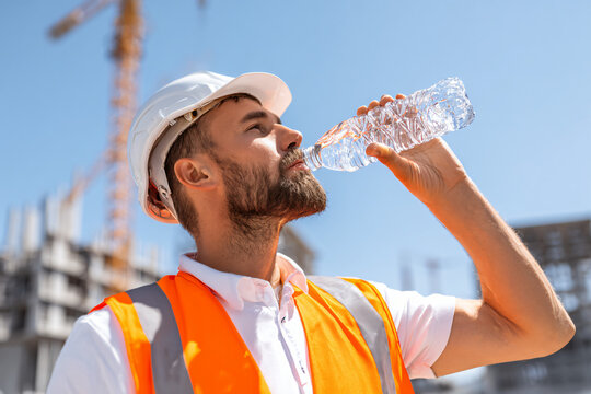 hardworking builder drinking water from bottle while taking short break under scorching sun