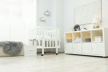 Beautiful baby room interior with stylish crib, other furniture and toys, low angle view