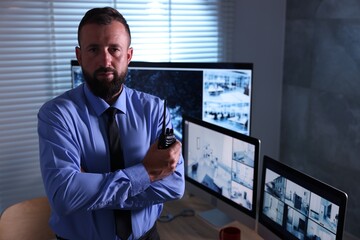Security guard with walkie talkie near CCTV cameras in office