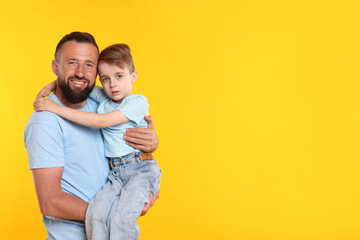 Family. Happy father and his son on yellow background. Space for text