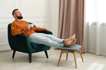 Harmony. Man with cup of drink in armchair at home