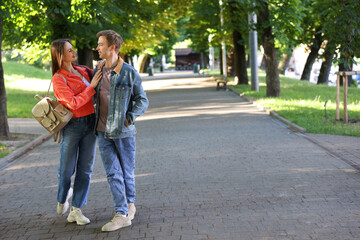 Obraz premium Lovely couple walking together in park, space for text