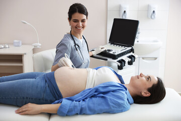 Sonographer conducting woman's prenatal ultrasound examination in clinic