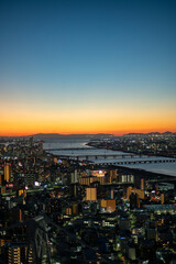 Fototapeta premium Cityscape of Osaka at dusk with illuminated buildings and river bridges, Japan