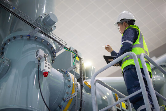Power station staff inspect industrial equipment carefully with safety gear and clipboard ensuring operational efficiency and safety in facility environment