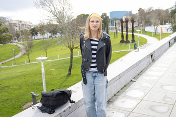 Teenage student wearing leather jacket and glasses in urban park