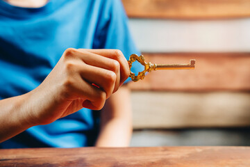 Elegant Golden Key Held by Hand on Wooden Surface