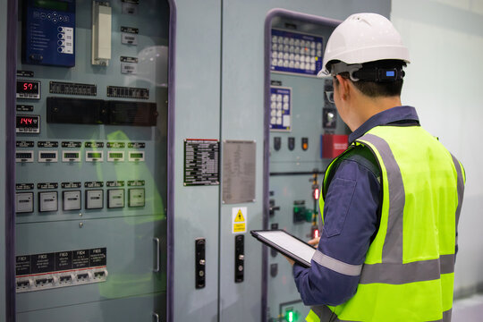 Power station engineer working with control panel wearing safety helmet and reflective vest in industrial environment focused on task - Powered by Adobe