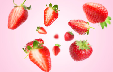 Yummy fresh strawberries swirling in air against pink background