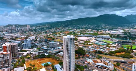 Flying away from the high-rise building in the scenery of Honolulu, Hawaii, USA. View on the city under the overcast sky.