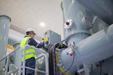 Gas insulated switchgear maintenance worker performing inspection in substation with safety helmet and vest