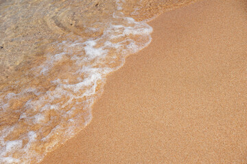 Minimal close-up of gentle sea wave washing over smooth sandy beach with wide copy space. Perfect for summer, travel, and relaxation themes.