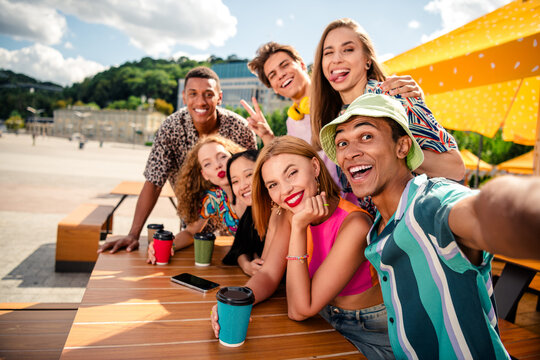 Group of friends enjoying outdoor leisure time on a sunny day in the city with beverages and great company - Powered by Adobe