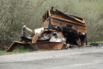 Abandoned burnt truck with rusted twisted metal left on a countryside roadside. The destroyed...