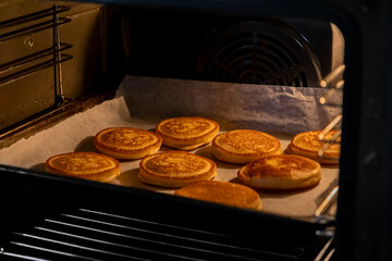 Delicious golden-brown pancakes baking on parchment paper inside a warm oven, perfect for a homemade breakfast, comforting snack, or family meal