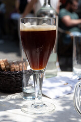 Belgian beer in glass in old brewery in Bruges, dubbel dark, tasty beverage, lunch with beer, tourist destination, Flanders, Belgium