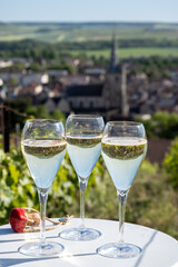 Pouring and tasting of dry sparkling wine brut, grand reserve, champagne in Ay-Champagne on green hilly vineyards in old wine making village in Vallee de la Marne, Champagne region, France
