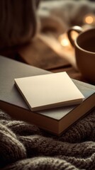 Cozy Winter Scene with Blank Note Paper on a Book by a Warm Cup of Coffee and Soft Knit Blanket, Atmospheric Lighting