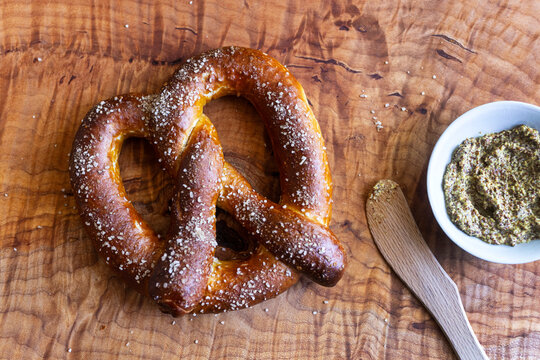 Freshly baked soft pretzels with coarse salt, served with a rustic grainy mustard dip, perfect as a traditional German snack or Oktoberfest appetizer.