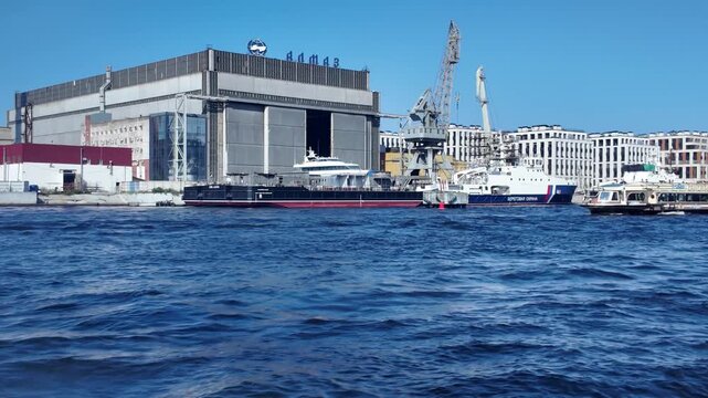 A boat speeds along the Neva River past the Almaz shipyard on a clear sunny day - St. Petersburg, Russia, July 16, 2025