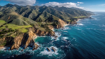 Coastal mountains meet the ocean.  Aerial view of rugged cliffs, lush green hills, and turquoise water