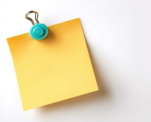 Blank yellow sticky note attached to a white surface with a teal colored binder clip