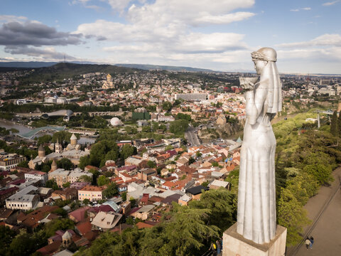 Aerial view of the Kartlis Deda statue overlooking the sprawling cityscape with its diverse architecture and the distant mountains, Tbilisi, Tbilisi, Georgia.