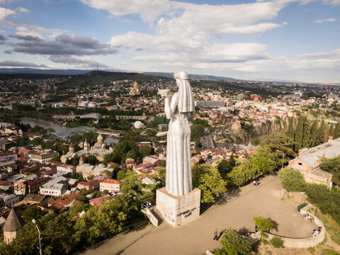 Aerial view of Kartlis Deda statue standing tall overlooking Tbilisi's old town with its terracotta rooftops and the Mtkvari River snaking through the cityscape, Tbilisi, Tbilisi, Georgia.
