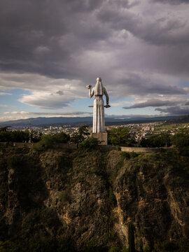 Aerial view of the Kartlis Deda statue standing tall against a backdrop of rolling hills and a dramatic sky, Tbilisi, Tbilisi, Georgia.