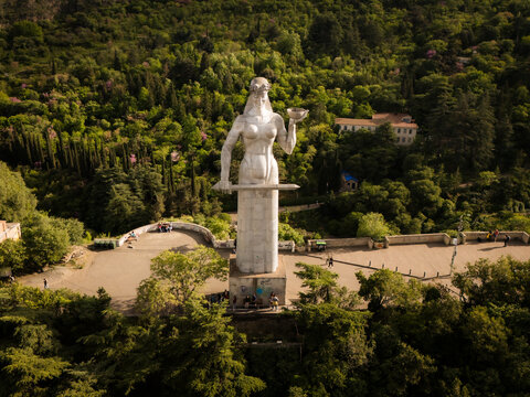 Aerial view of Kartlis Deda statue standing tall amidst the lush greenery, with its silver dress and bowl reflecting the sunlight, Tbilisi, Tbilisi, Georgia.
