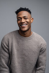 Fototapeta premium Confident young man with a bright smile wearing a cozy grey sweater against a neutral background