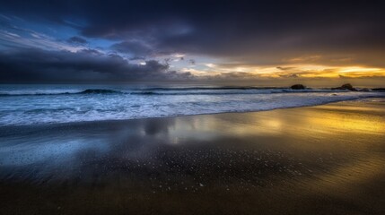 Fototapeta premium Dramatic coastal sunrise/sunset; stormy clouds meet golden light on beach