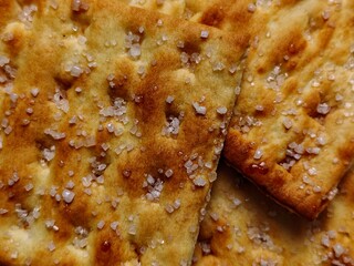CloseUp of Golden Crackers Sprinkled with Coarse Salt Crystals Macro Food Photography.
