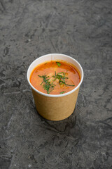 Solyanka soup in a disposable container on a gray background