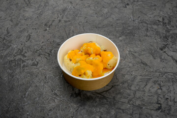 Ukrainian dish stewed white cabbage with cheese in a disposable dish on a gray background