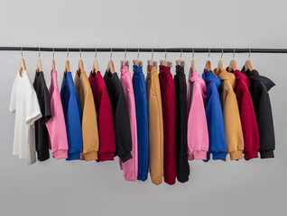 Hoodies and t-shirts of different colors are neatly arranged on hangers in a minimalist setup, highlighting their comfortable fabrics and casual styles.