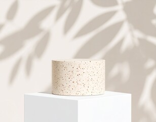 Beige Speckled Cylinder on White Pedestal with Leaf Shadows