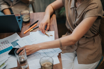 Business professionals working together around a desk with documents, charts, and beverages, fostering teamwork.