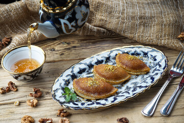 Fried sweet pies on a plate on a background with tea
